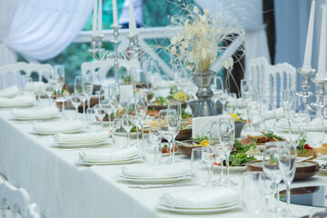 Empty banquet hall ready to receive guests on the summer terrace. white festive table