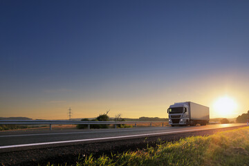 Landscape with a moving truck on the highway at sunset.