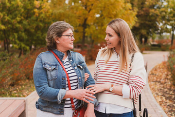 charming women in casual style, mom and daughter are walking in a beautiful autumn park