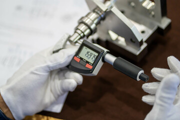 Industrial worker measure detail with digital caliper micrometer at factory workshop