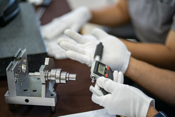 Industrial worker measure detail with digital caliper micrometer at factory workshop