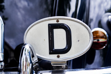 Oval badge made of white sheet metal with black letter D to mark the country of origin Germany on a...