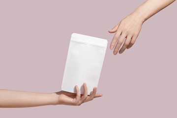 Female hand holds white cardboard packaging for tea/coffee/snack on pink background. Branding and...