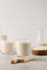 Glasses of vegetable rice milk and a jug on a gray background. Vegetarian food, lactose free milk. 