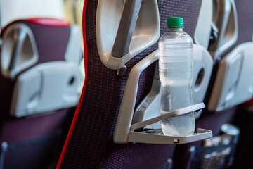 Battle of still water on a bottle holder of a plastic chair on a bus. Travel concept and importance of drinking liquid on a trip.