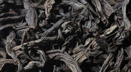 Dried black tea leaves as background.