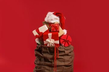 Christmas presents in a Santa’s bag, over a red background 