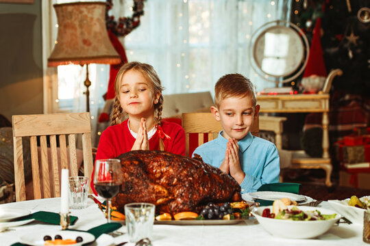 Kids on a thanksgiving dinner sitting together and praying, 50s retro style 
