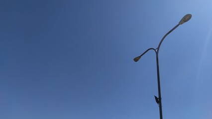 Photo of a lamp post in a city square park in the Cikancung area, isolated on a bright blue sky...