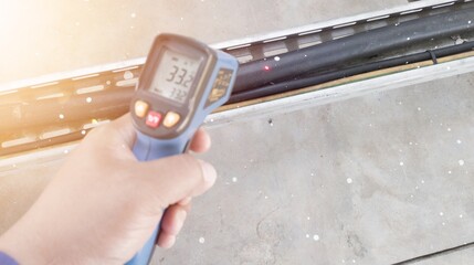 checking the temperature of industrial electrical cables using an infrared thermometer gun,...