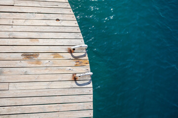 Wooden planks on the pier above the blue sea. Wooden planks on top of the water.