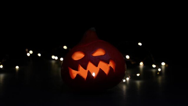 Carved Halloween pumpkin with lights on background. Dark key footage.