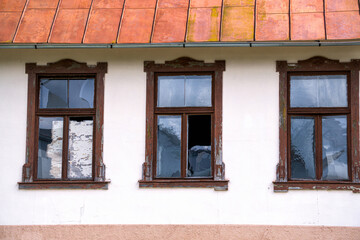 Broken windows in an old building against a white wall.
