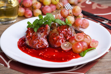 Warm salad with chicken liver and grapes on the plate. Warm salad from turkey liver. Warm salad...