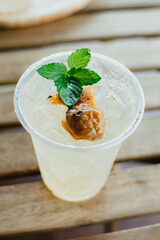 Close up of iced plum juice with soda and peppermint on wood table. Refreshment drink.