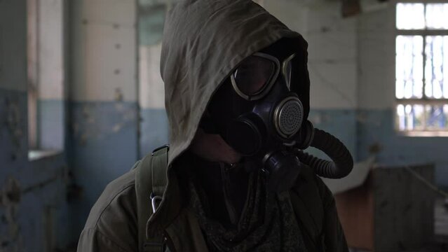 Male stalker in a gas mask in a destroyed building. Concept of survival after war or apocalypse