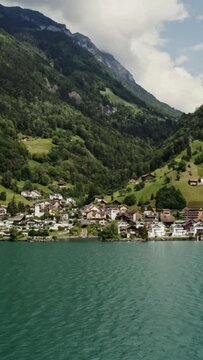 Modern village in a lowland between the Alpine mountains on the lakeshore