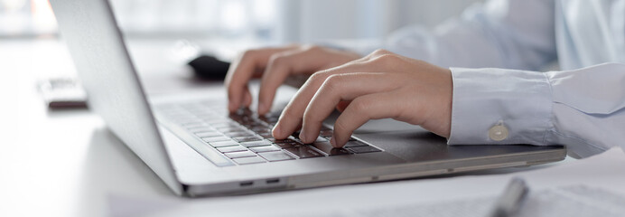 Businesswoman's hand presses on a laptop keyboard, World of technology and internet communication,...