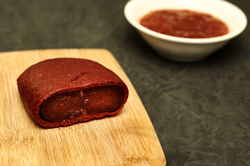 basturma on a wooden cutting board next to a plate with spices