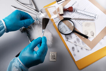 Forensic fingerprinting, forensic expert handles a glass goblet with a fingerprint brush