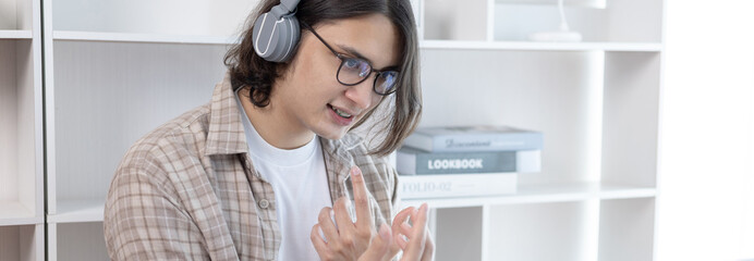 Young Asian men are greeting friends and teachers through video chats and greeting them with cheerful expressions, Online communication , Stay home, VDO Call, Social distancing, Internet learning.