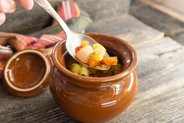 stewed vegetables in a clay pot on a wooden background. food concept.