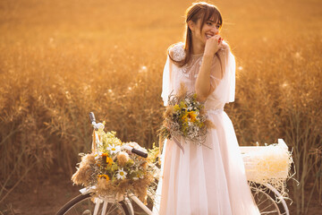 Woman wearing beautiful dress standing in the field with bouquet of flowers