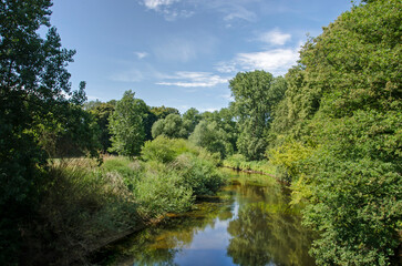 Fototapeta na wymiar View along the tranquil stream of the river Ems in a lush and green landscape near Münster, Germany, on a summer day