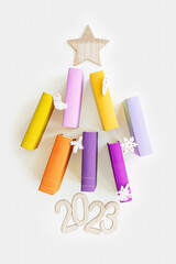 Christmas tree of colors paper books, New Year 2023 fir shape with star on top, bright colorful covers of books as holiday Christmas tree. Reading, studying, education concept. Top view