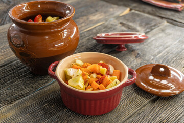 stewed vegetables in a clay pot on a wooden background. food concept.
