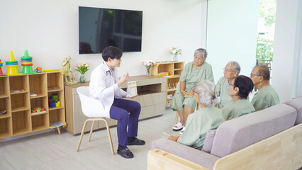 An Asian doctor talking to a group of old elderly patient or pensioner people smiling, relaxing, having fun together in nursing home. Senior lifestyle activity recreation. Retirement. Health care