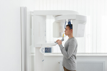 A young man has a computed tomography of the jaw, a circular snapshot of the jaw in modern dentistry. Prevention of caries, prosthetics and dental treatment. Radiology, panoramic scanner.