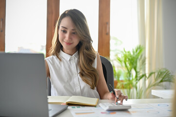 Beautiful Asian female entrepreneur or businesswoman using laptop computer.