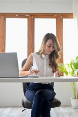 Attractive Asian businesswoman using calculator to calculate her passive income on the report.