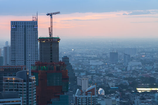 Construction site with cranes in the business district at dusk (Bangkok, Thailand)