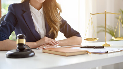 A professional female lawyer or business legal consultant in formal suit sits at her office desk.