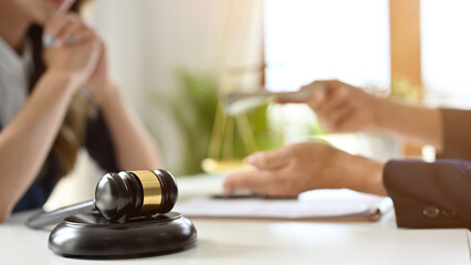 Judge's gavel is on the table over a blurred background of a businessman giving a bribe to a lawyer