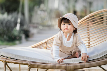 Happy cute baby sit on a chair outdoor in the park. 1 year baby in the park use as concept of play, health, mood and motion of baby and kid development.