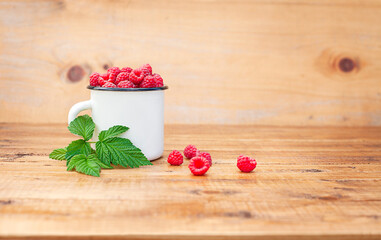 white mug with raspberries on wooden background with copy space
