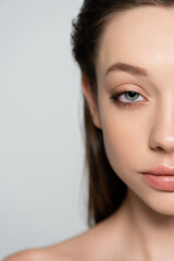 Naklejka premium cropped view of young woman with blue eye and bare shoulder isolated on grey