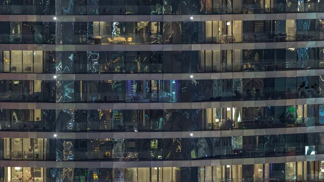 Outside view of windows in apartments of a high class building at night timelapse. Glowing lights in skyscraper with reflections