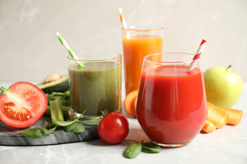 Delicious vegetable juices and fresh ingredients on light grey table