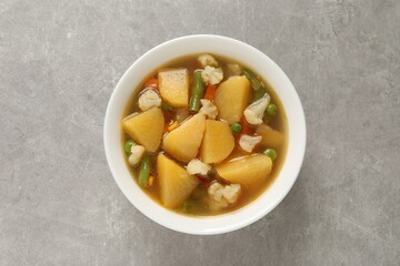Bowl of delicious turnip soup on light grey table, top view