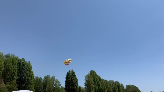 A boat pulls a parachute across the sea with two tourists flying over the shore. Entertainment and active recreation of people at the sea in summer.