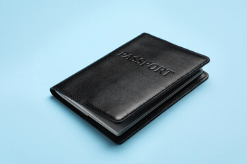 Passport in black leather case on light blue background