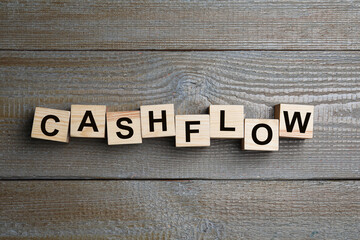 Cubes with phrase Cash FLow on wooden background, flat lay