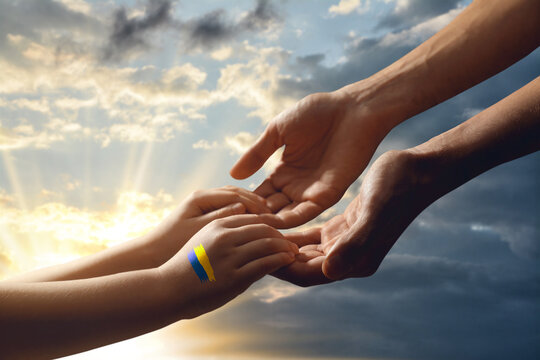 Help for Ukraine. People holding hands with drawing of Ukrainian flag and beautiful sky with clouds at sunset on background, closeup