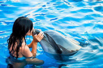 Portrait of young Caucasian woman kiss dolphin in pool water of Batumi delphinarium. Swim with...