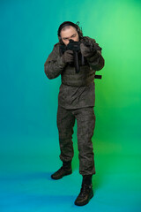 soldier in the studio on a green background with colored light. a man in military uniform with a gun, rifle or machine gun. military. airball player