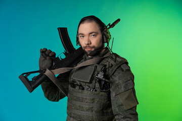 soldier in the studio on a green background with colored light. a man in military uniform with a...